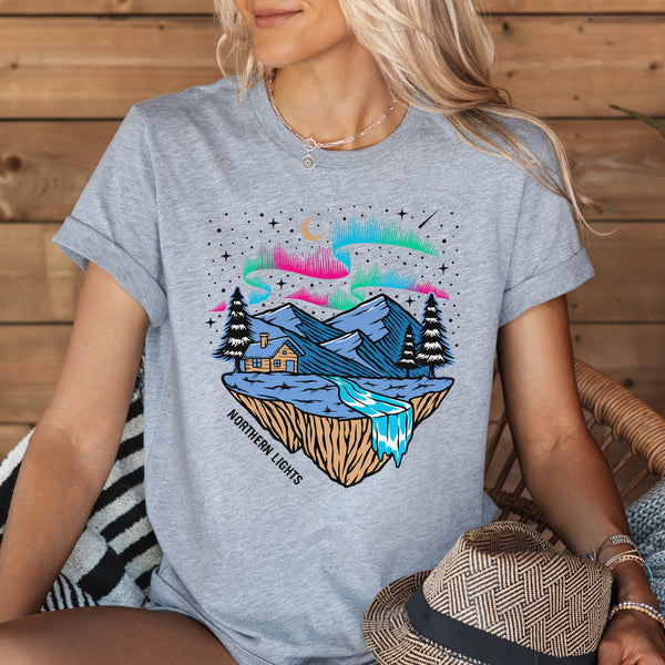 woman wearing a grey t-shirt with Northern Lights and the mountains