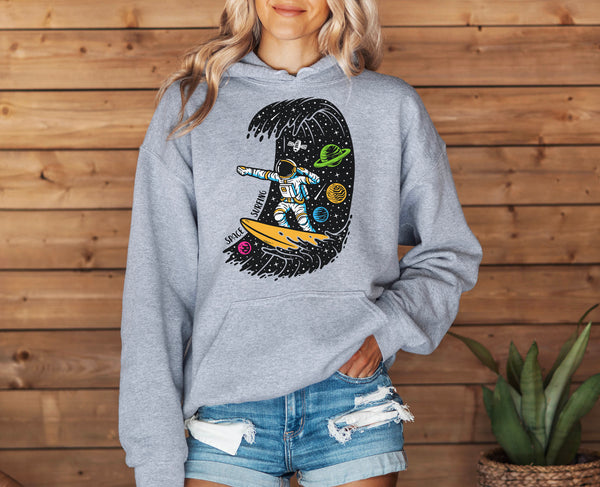 woman wearing a grey hoodie with an astronaut surfing through a space wave full of planets